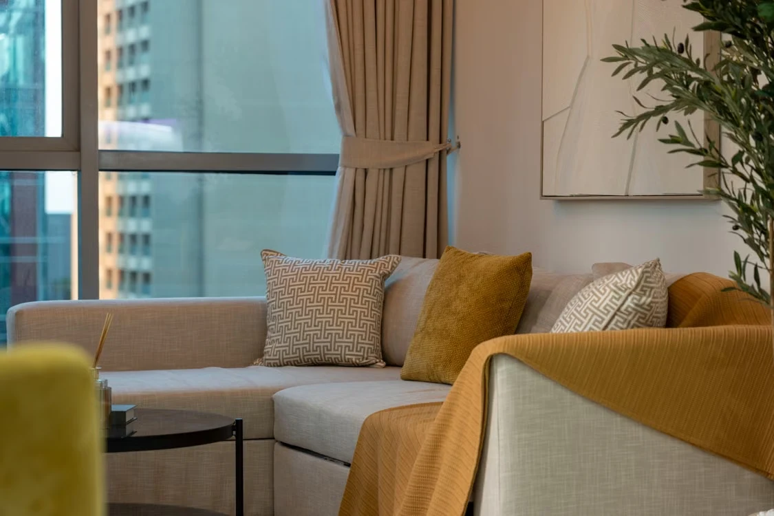 Dubai living room with a beige sofa, patterned cushions, glass coffee table and large window